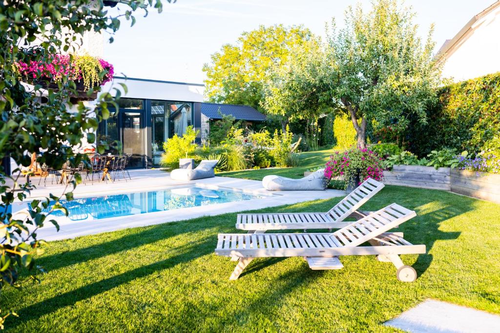 two white lounge chairs sitting in the grass near a pool at 110qm Countryside Loft in Neufahrn in Niederbayern