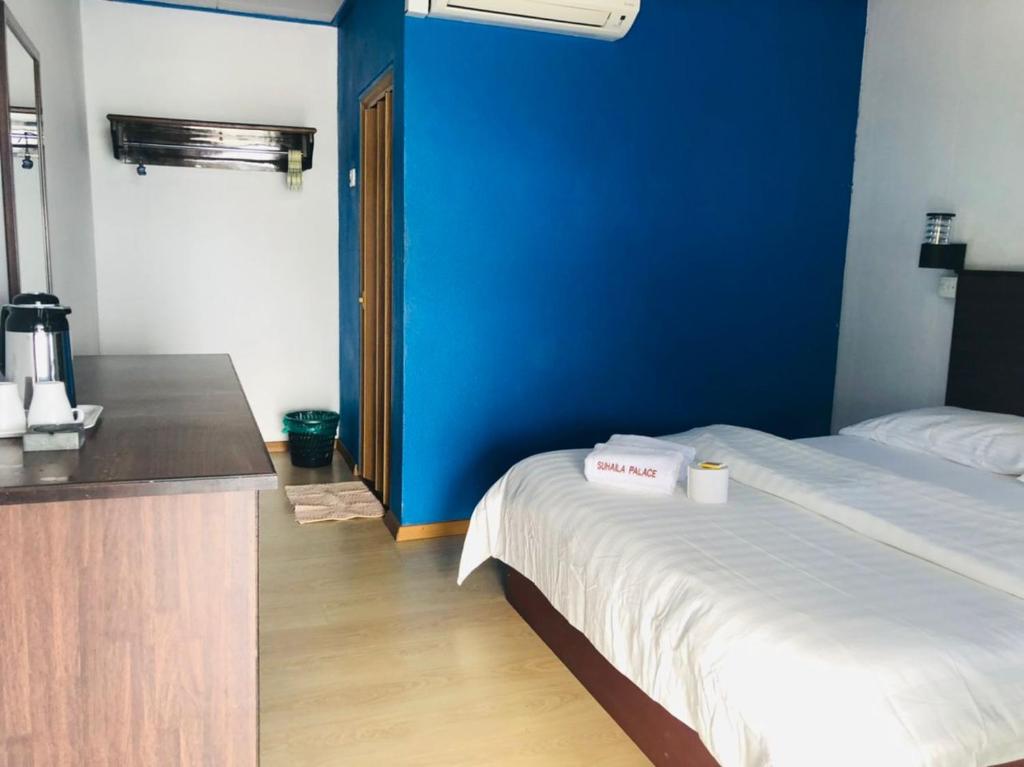 a room with a bed and a blue wall at Suhaila Palace in Perhentian Islands