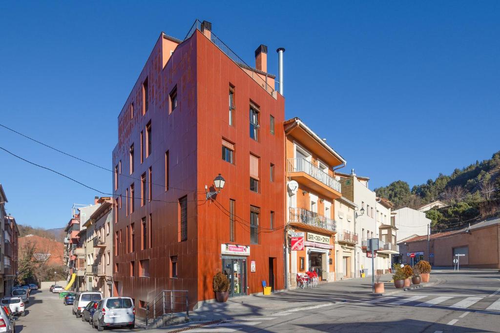 ein rotes Backsteingebäude auf einer Stadtstraße mit parkenden Autos in der Unterkunft Vipimmoble ! in Guardiola de Berga