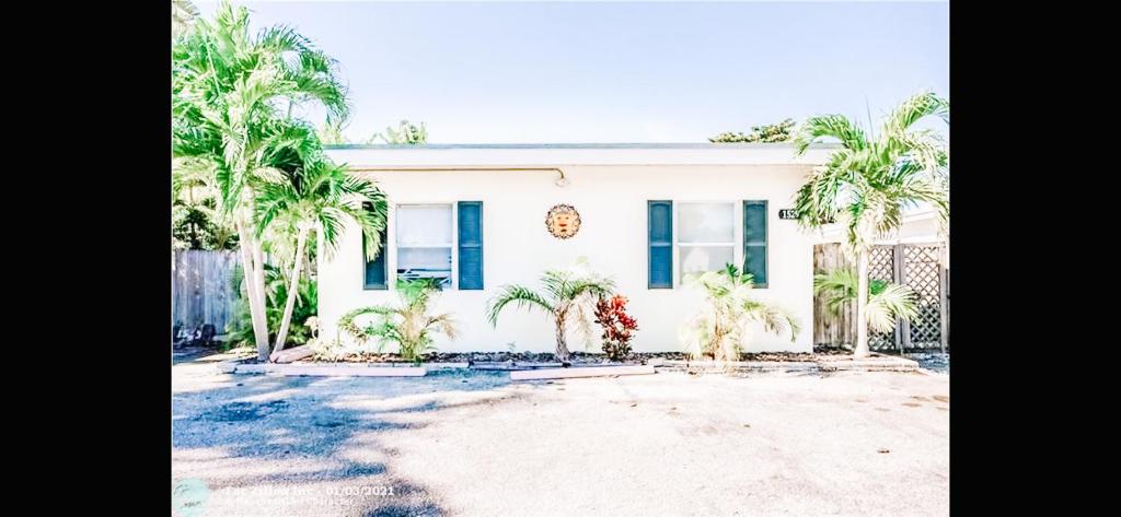 a white house with palm trees in front of it at Lovely Bohemian Apartment in Fort Lauderdale