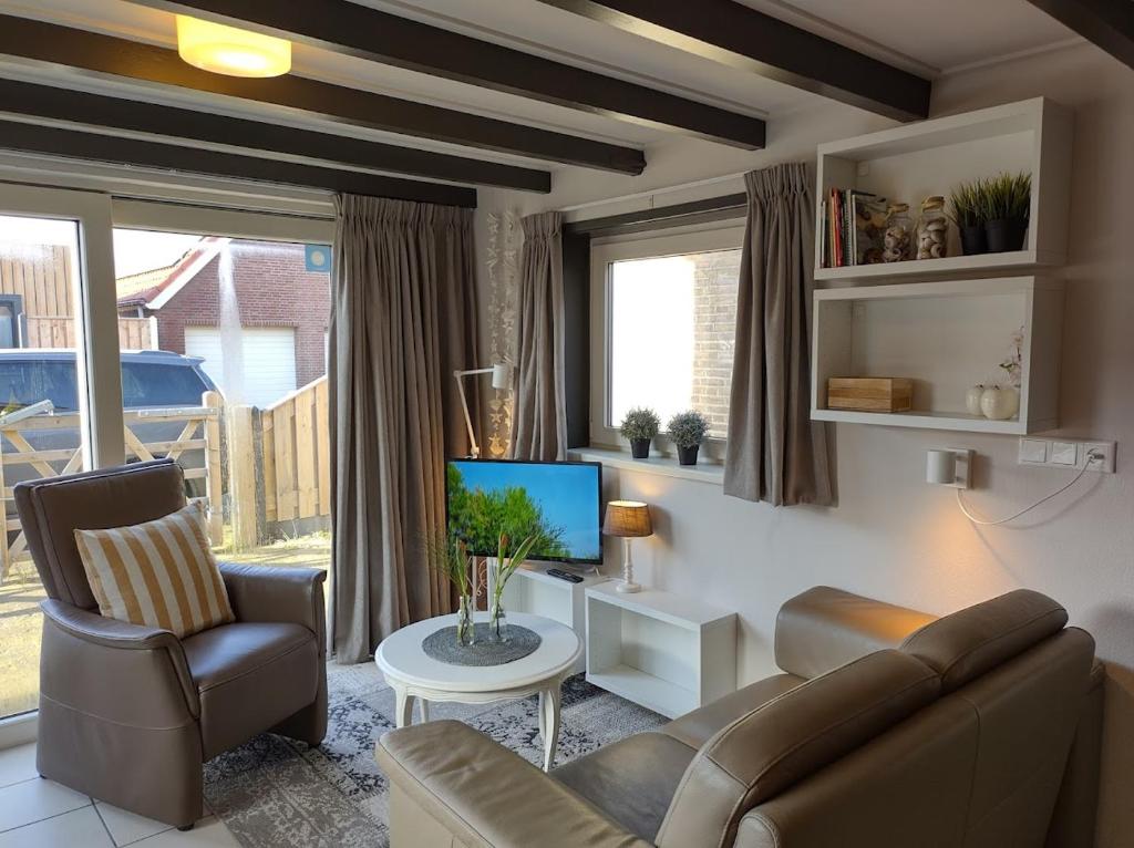 a living room with a couch and a television at TINY HOUSE MIMI Bed by the Sea - Adults only in Zoutelande