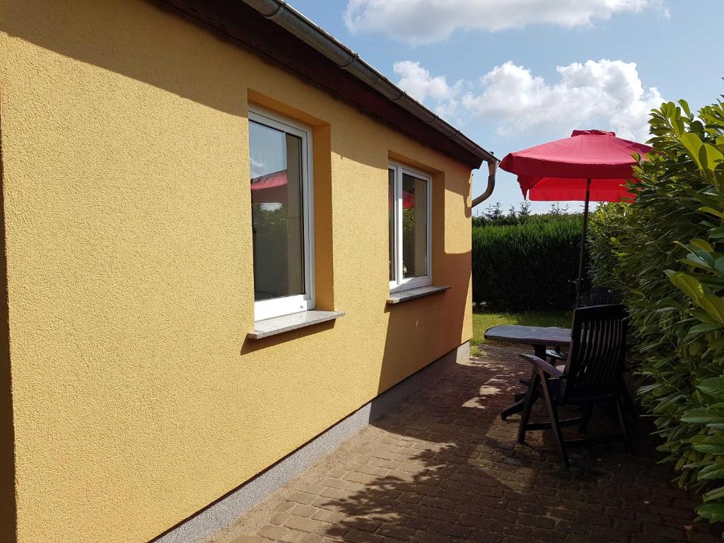 a yellow house with a table and an umbrella at Ruegen Fewo 111 in Drewoldke