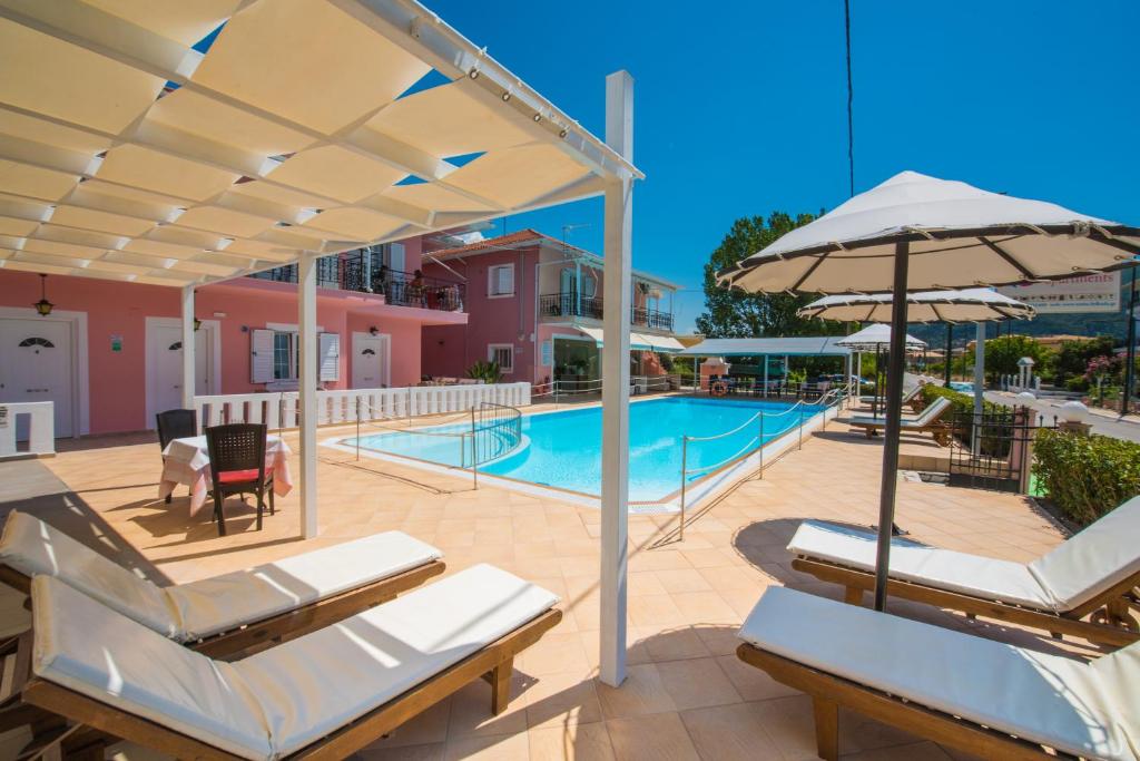 a pool with chairs and umbrellas next to a building at Xenia Apartments in Vasiliki