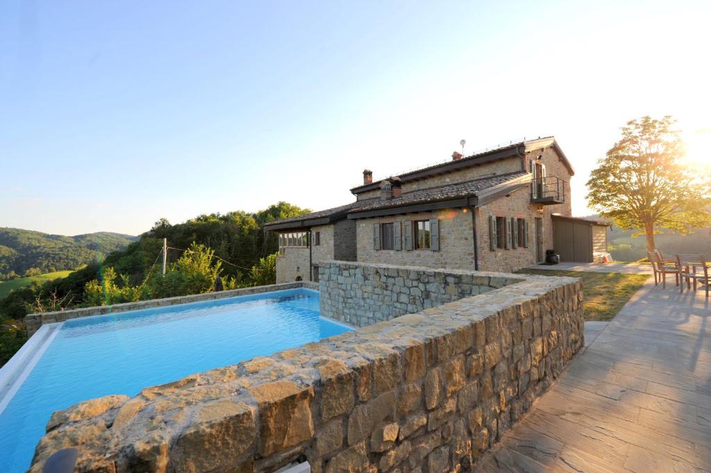 a house with a swimming pool and a stone wall at La Collina Zocca in Zocca