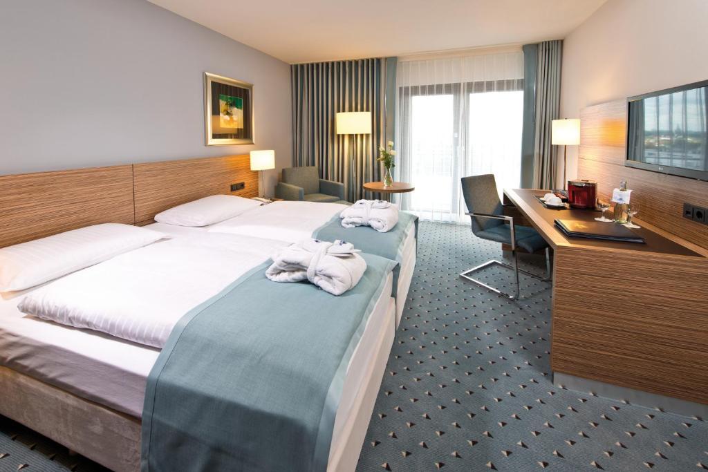 a hotel room with two beds and a television at Maritim Hotel Darmstadt in Darmstadt