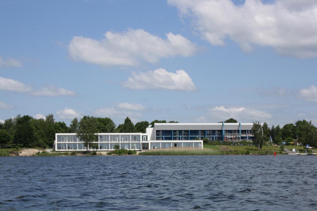 un grande edificio sulla riva di un corpo idrico di Strandhotel Senftenberger See a Senftenberg