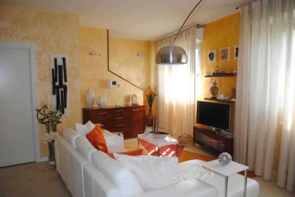 uma sala de estar com um sofá branco e uma televisão em Appartamento Minerva em Rimini