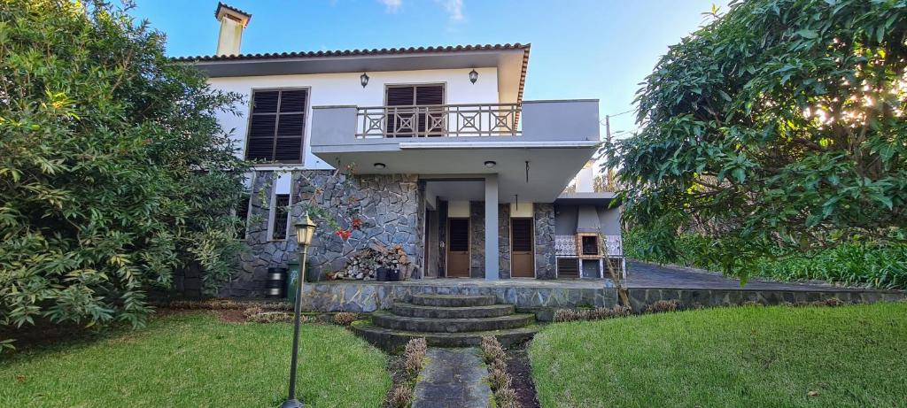 ein weißes Haus mit Balkon auf einem Hof in der Unterkunft Descanso do Guerreiro in Ribeira Grande