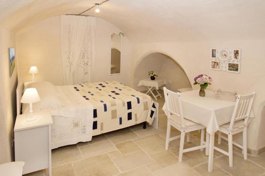 モノーポリにあるLocazione turistica Casa Liùの白いベッドルーム(ベッド1台、テーブル、椅子付)
