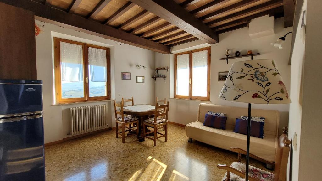 eine Küche und ein Wohnzimmer mit einem Tisch und einem Sofa in der Unterkunft Finestra sulla val d'Orcia in San Quirico dʼOrcia