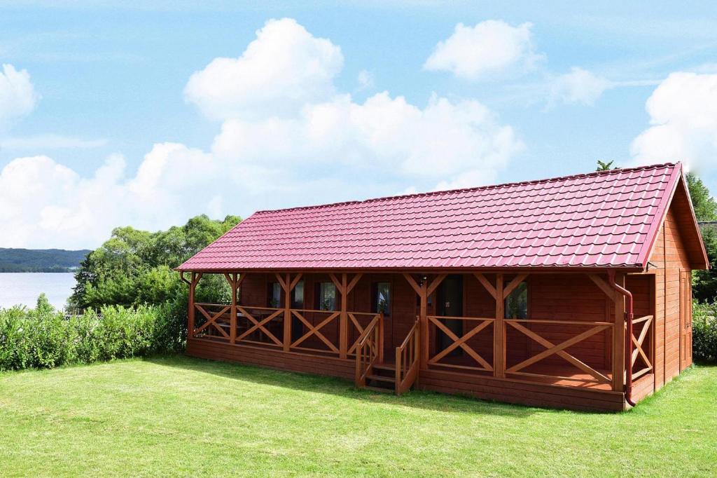 un pavillon en bois avec un toit rouge sur une pelouse dans l'établissement Beautiful Bungalow in Nadole with Roofed Terrace, à Nadole