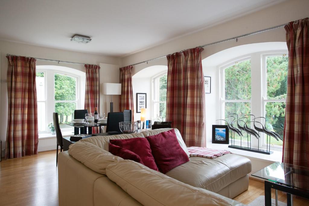 ein Wohnzimmer mit einem Sofa und einigen Fenstern in der Unterkunft Old School Apartments With A View in Fort Augustus