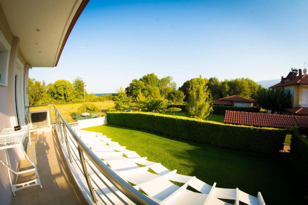 balkon z białymi krzesłami i trawnikiem w obiekcie Am Meer w mieście Leptokaria