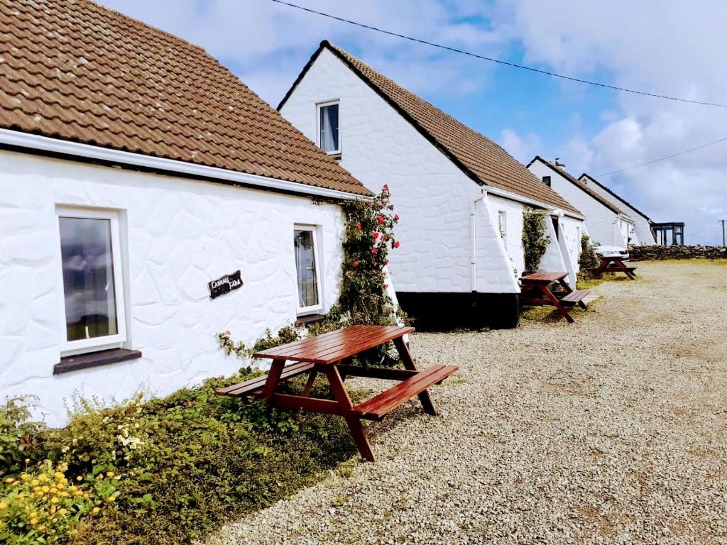 a wooden bench in front of a white building at Doonbeg Holiday Cottages in Doonbeg