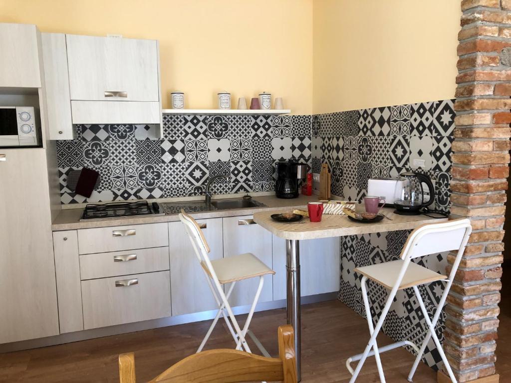 a kitchen with white cabinets and a table and chairs at Casa Teodoro - Gelsomino & Ulivi in Tignale