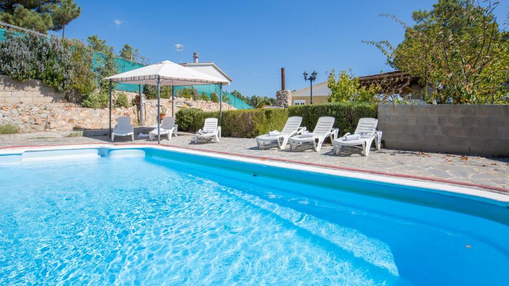 een zwembad met stoelen en een parasol bij Villa Ara - Lloret de Mar in Mont Barbat