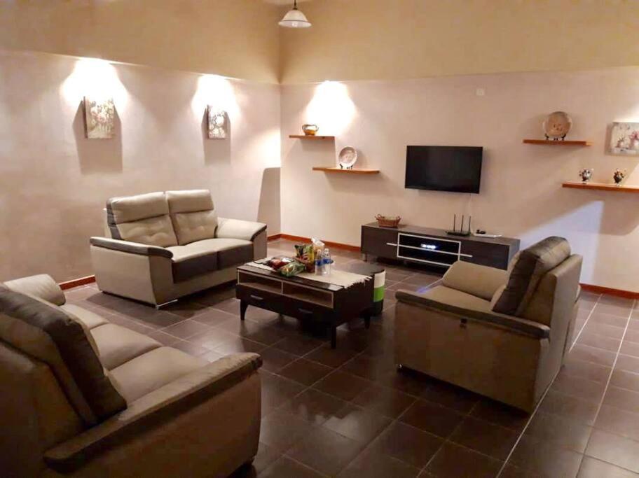 a living room with couches and a flat screen tv at 4-6人家庭 Cozy Home @ Kutoba Square in Tawau