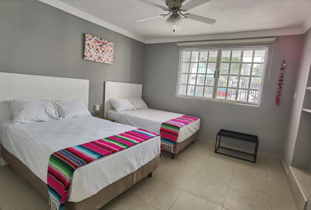 Un dormitorio con dos camas y una ventana. en Casa Buba, en Cozumel