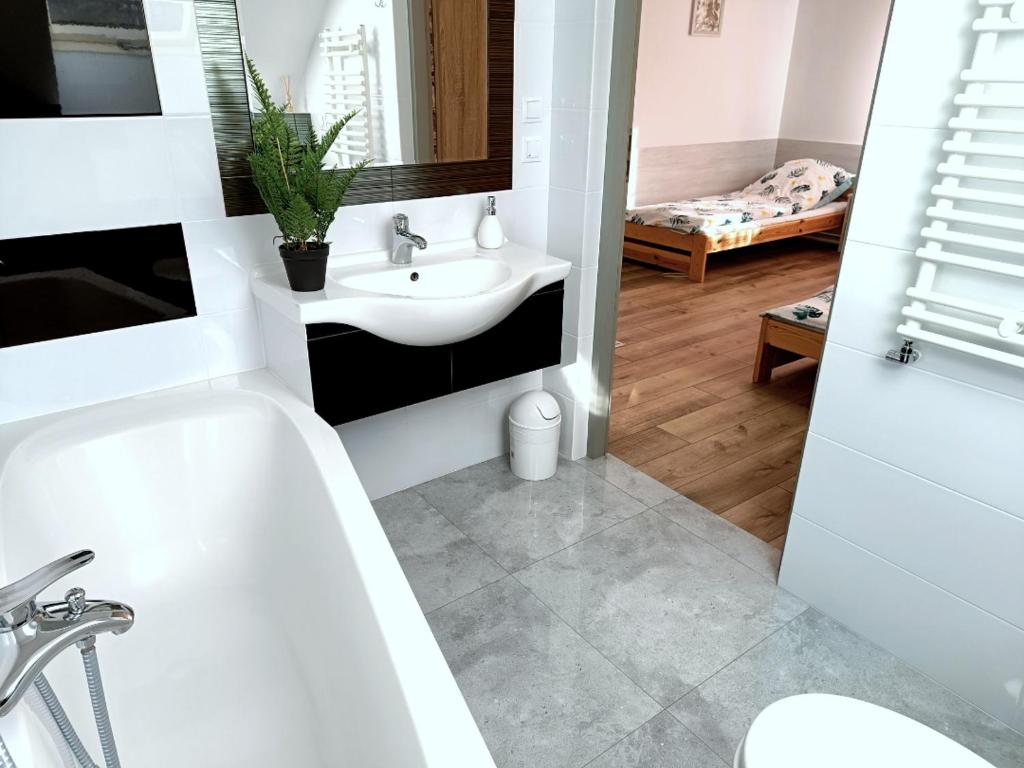 ein Badezimmer mit einer weißen Badewanne und einem Waschbecken in der Unterkunft Kukułka - Agroturystyka Nad Rzeczką. in Siennica