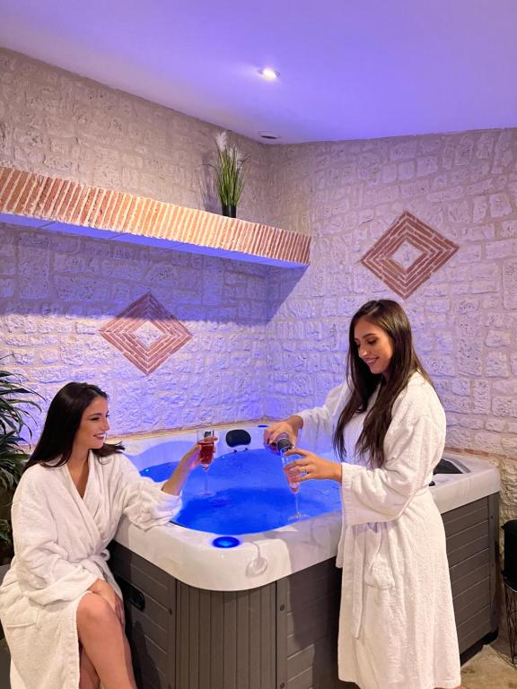 twee vrouwen in een badkamer met een bad bij Suite Privative Jacuzzi Sauna de la Villa Del Castagnol in Saint-Nexans