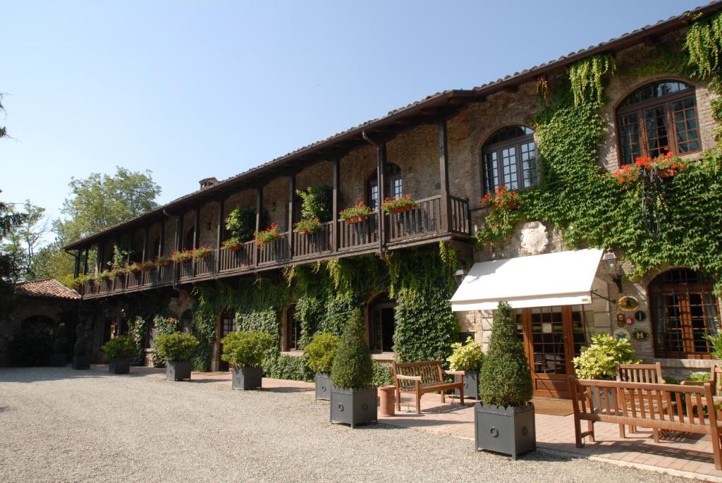 ein mit Efeu bedecktes Gebäude mit Bänken und Tischen in der Unterkunft Residenza Torre di San Martino in Gazzola Di Rivalta