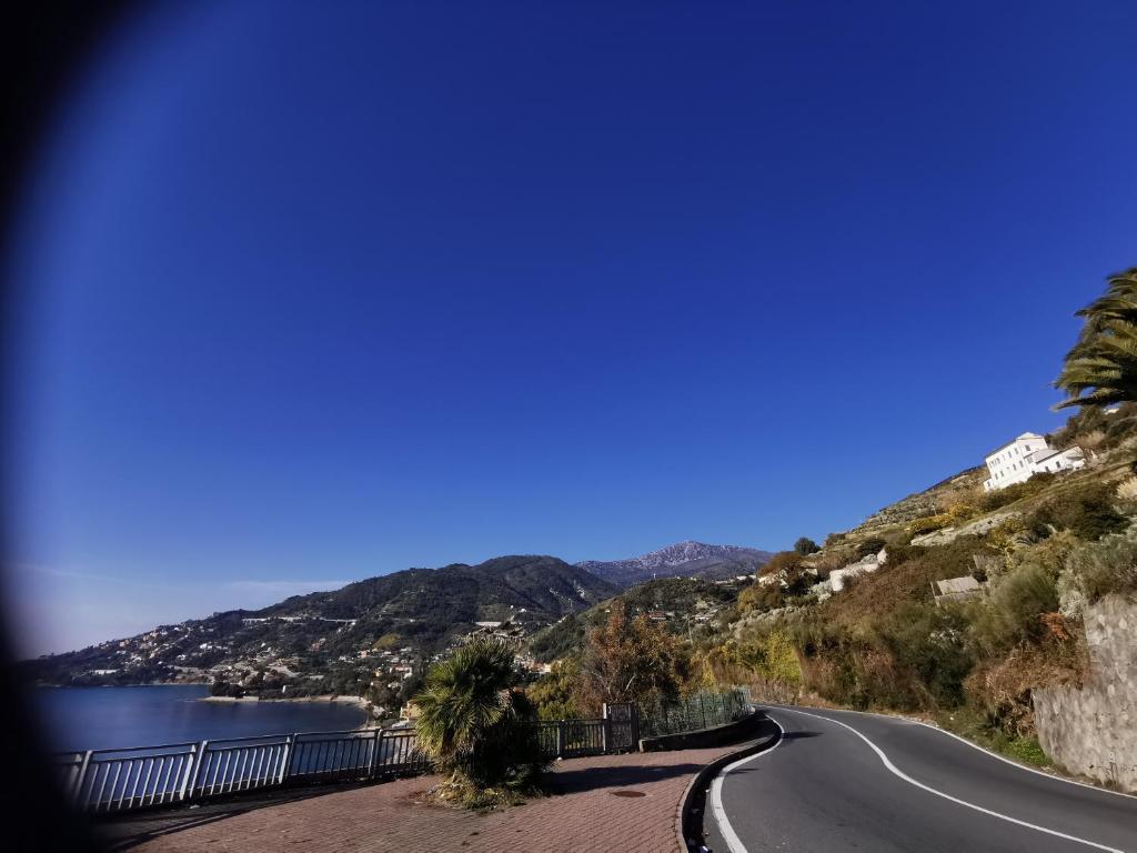 a road on a hill next to a body of water at Romantic Casa Lorenzina Affittacamere in Ventimiglia
