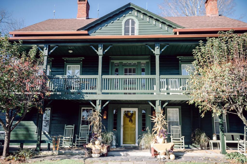 a green house with a porch and a yellow door at Fox & Bear Lodge in Glenwood