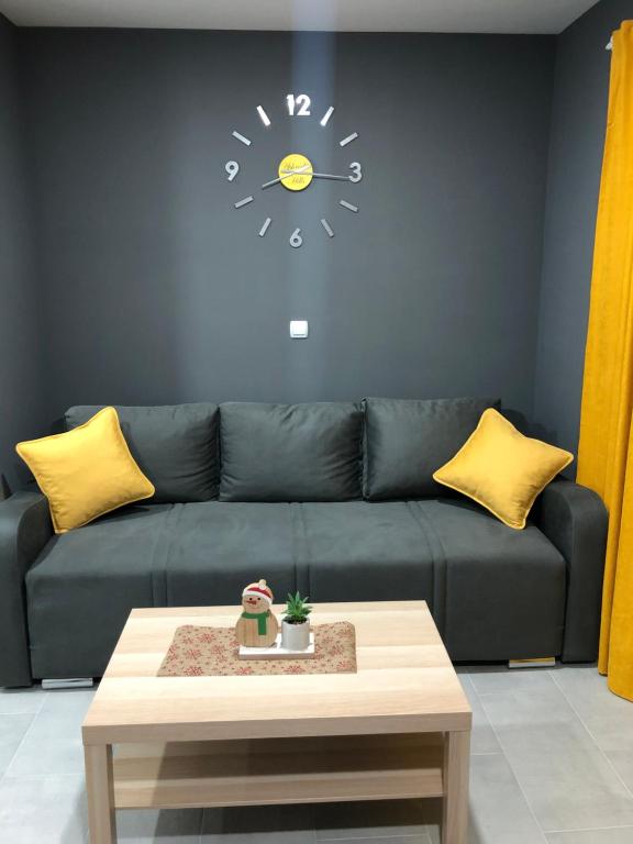 a living room with a couch with a clock on the wall at Aphrodite Hills Apartments-Stara Planina in Crni Vrh