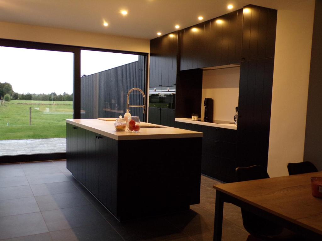 a kitchen with black cabinets and a large window at Riposo in Poperinge