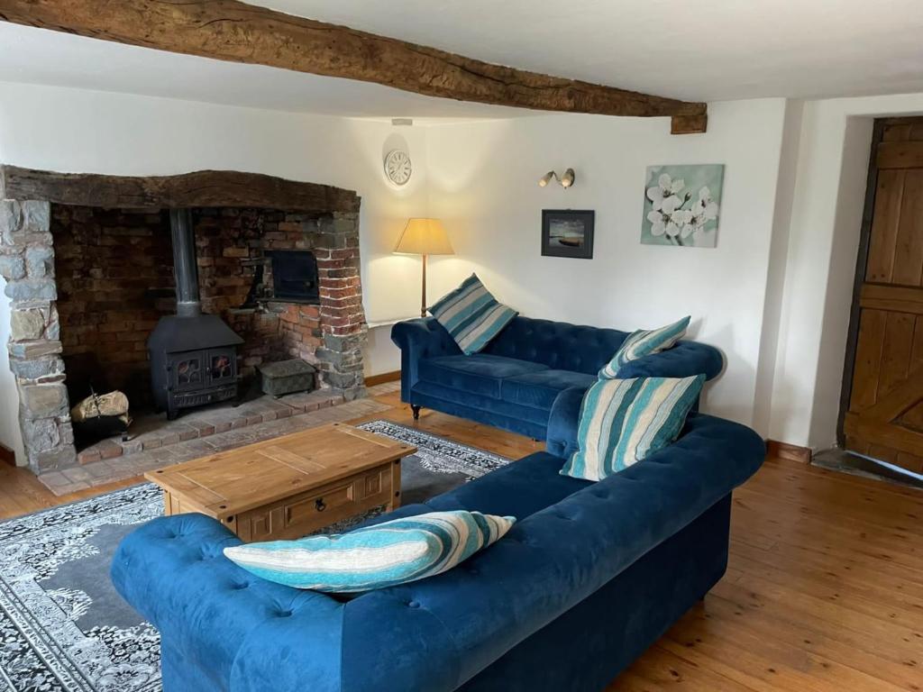 a living room with a blue couch and a fireplace at Stibb Farm Cottage at Sandymouth in Bude