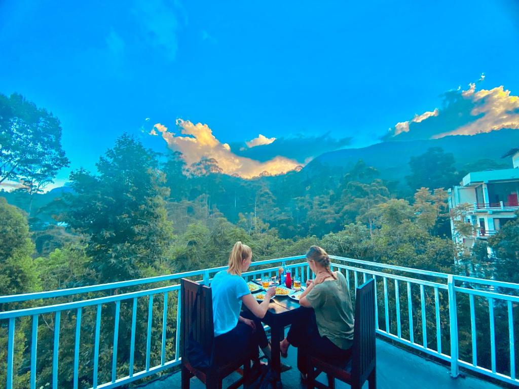 un hombre y una mujer sentados en una mesa en un balcón en Adams Peak Inn, en Nallathanniya