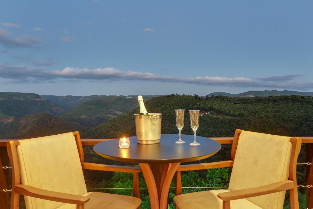 una mesa y dos copas de vino en un balcón en Pousada Janela do Vale, en Nova Petrópolis