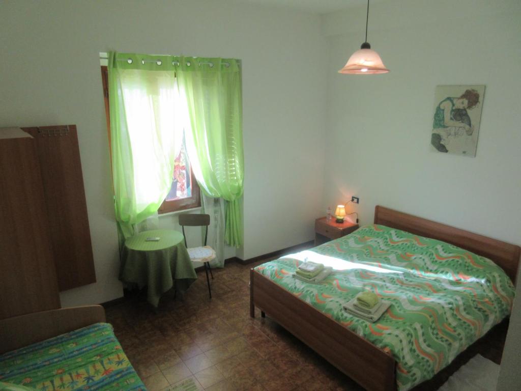 sypialnia z łóżkiem, krzesłem i oknem w obiekcie Su Pasu B&B w mieście Orosei