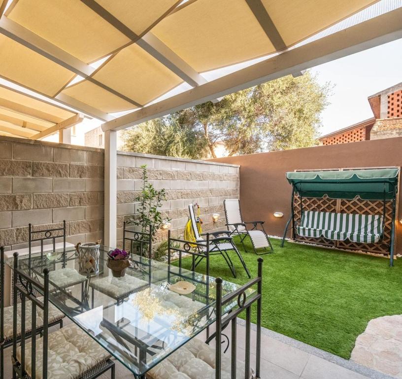 d'une terrasse avec une table, des chaises et une pelouse. dans l'établissement Casa Helen, à SantʼAntìoco