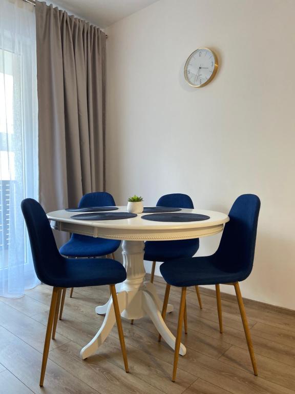 uma mesa com quatro cadeiras e um relógio na parede em Napoca Apartament em Floreşti