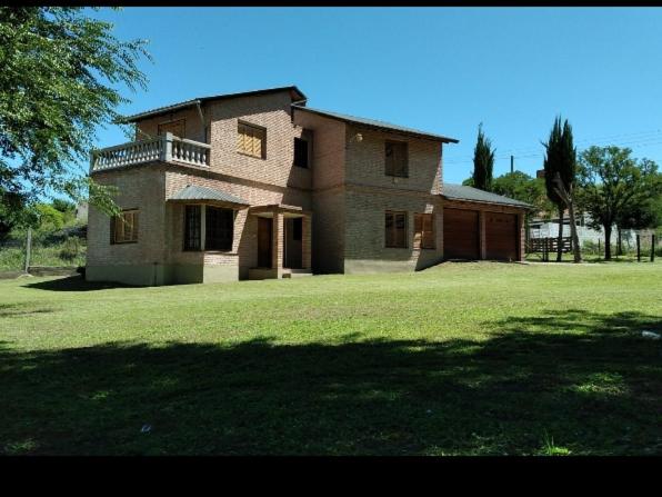 a large house on a grassy field with a tree at La Churrasquita in Salsipuedes