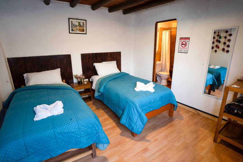 sypialnia z 2 łóżkami z niebieską pościelą i lustrem w obiekcie Hostal Teatro Inka w Cuzco
