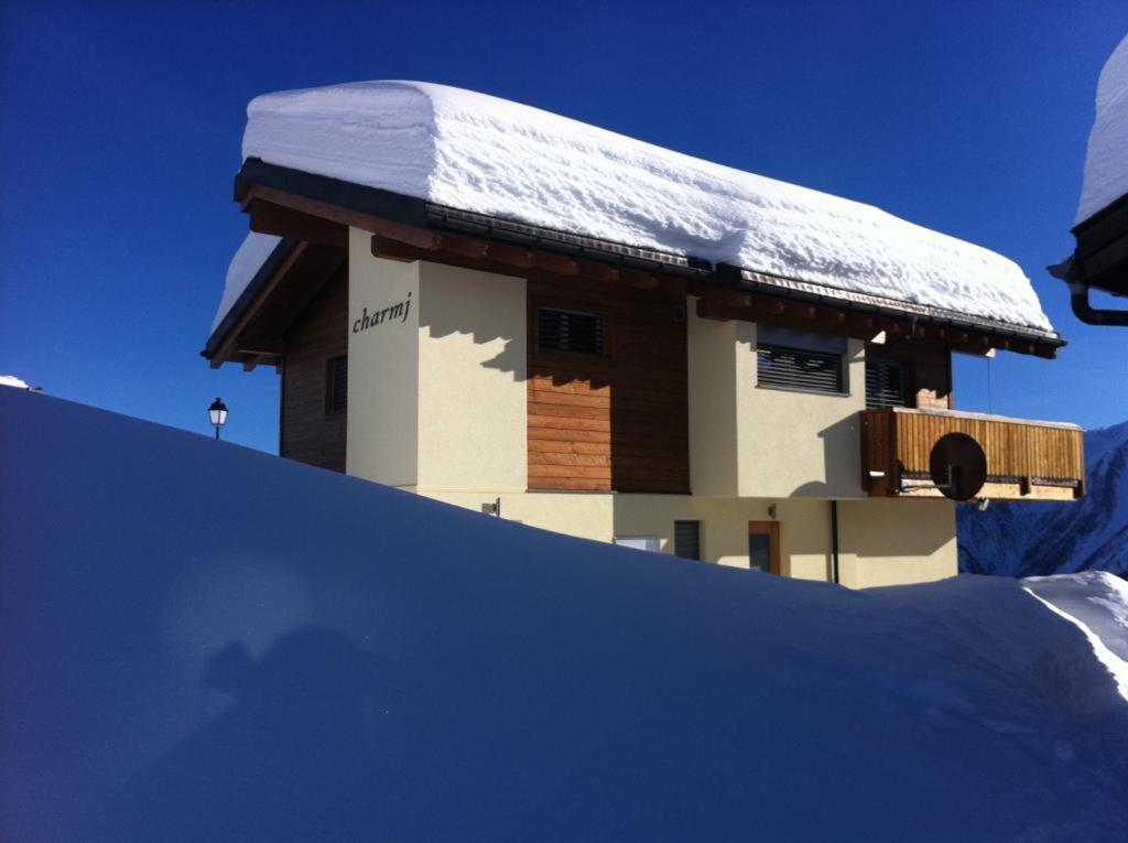 um edifício coberto de neve no topo de uma encosta coberta de neve em Chalet Charmj, Bettmeralp em Bettmeralp