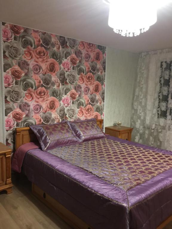 een slaapkamer met een bed met een muurschildering van rozen bij Apartamenti MĀRA in Madona