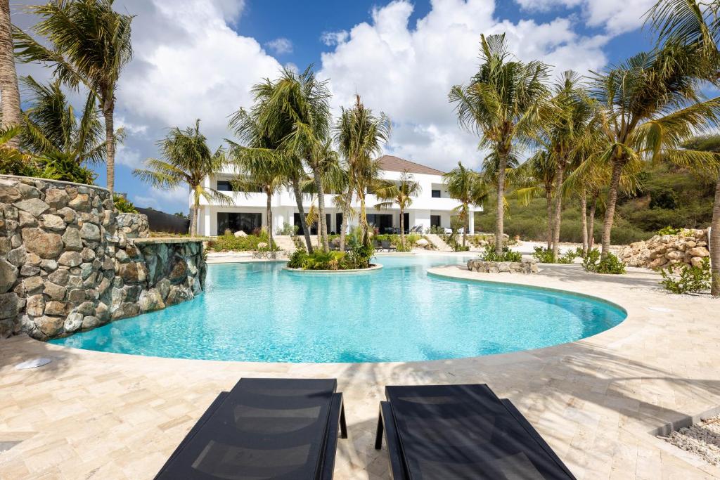een zwembad met palmbomen voor een huis bij The Reef - Blue Bay Golf & Beach Resort in Willemstad