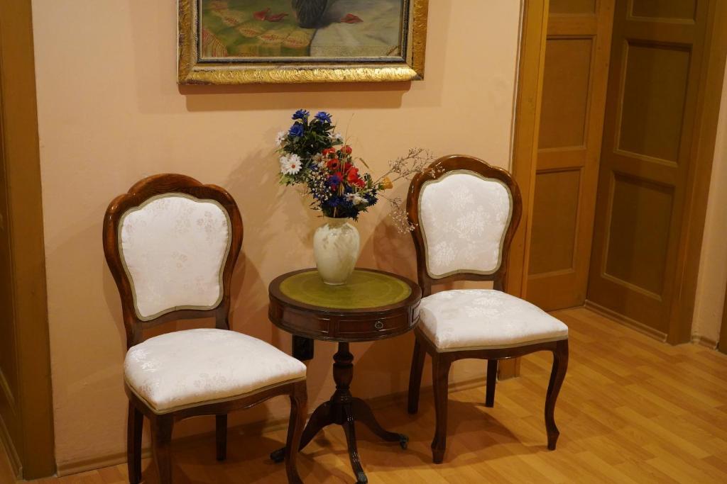 a table with two chairs and a vase with flowers at Kamil Apartments, Lux, 95m2 in Karlovy Vary