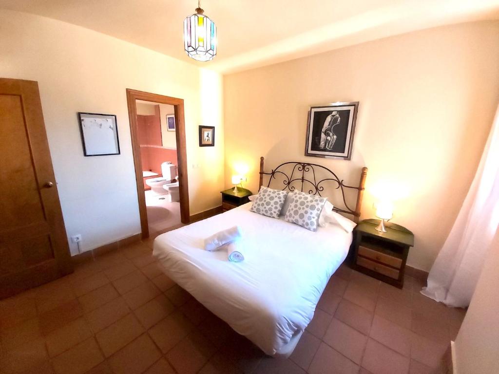 a bedroom with a white bed and a bathroom at Plaza Andalucía Edificio Enebro 4-6 pax in Sierra Nevada