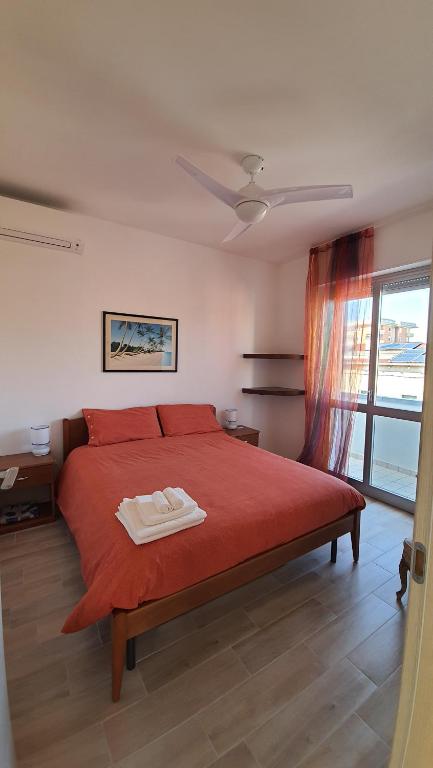 ein Schlafzimmer mit einem roten Bett und einem Fenster in der Unterkunft casa vacanza fronte mare fano sassonia in Fano