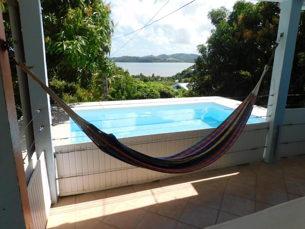 a hammock on a porch next to a swimming pool at Villa KANEPICE in La Trinité