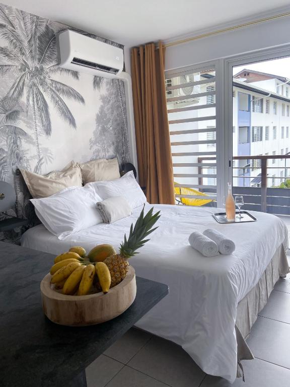 卡宴Un Palmier dans la chambre, studio de standing的一间卧室，床上放着一碗水果