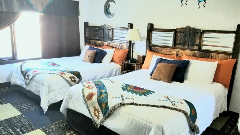 a bedroom with two beds with white sheets at Adobe Sands Motel in Panguitch