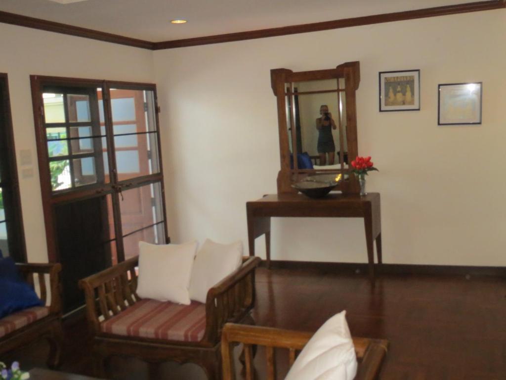 a living room with a mirror and a table and chairs at Green Papaya Villa in Hua Hin