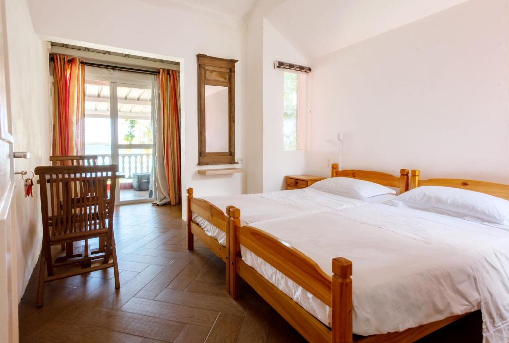 una camera con un grande letto e una sedia in legno di Colibri Beach Villas a Trou d'Eau Douce