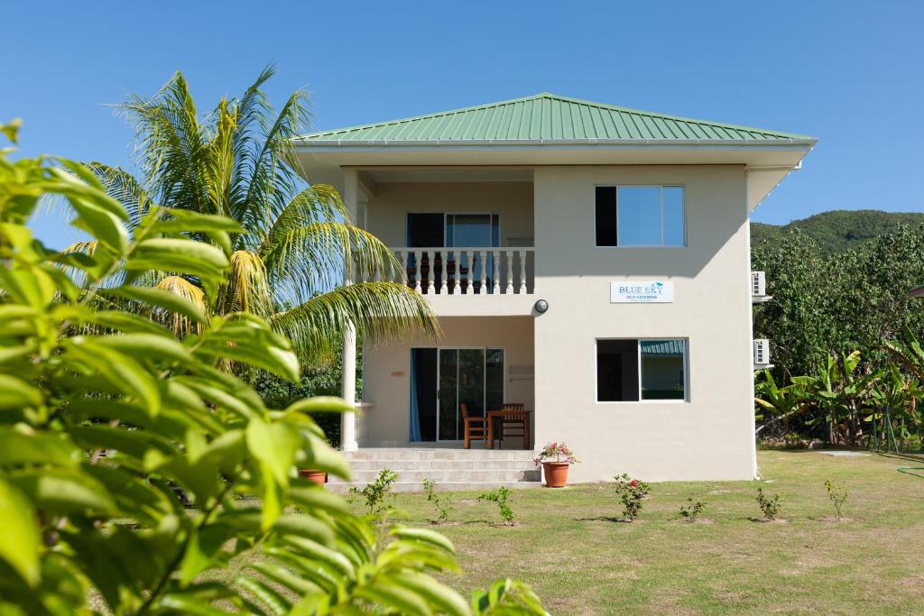 uma casa branca com um telhado verde em Blue Sky Self Catering em Grand Anse