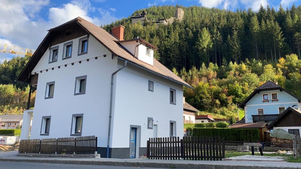 una casa blanca con una valla de madera frente a una montaña en Center House, en Ramingstein